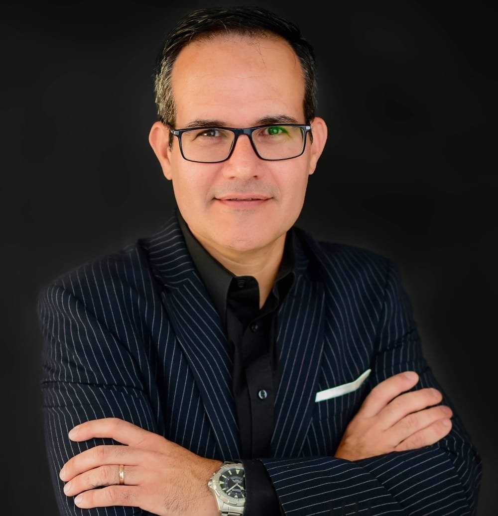 Dr. Rodrigo Schenckel, de terno risca de giz e braços cruzados